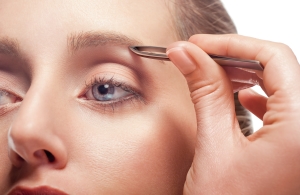 Woman plucking eyebrow